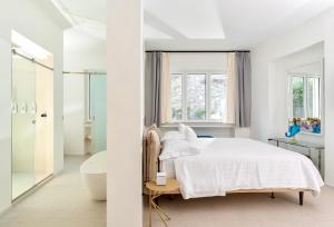 Le donne di Capri - Charming apartments in Capri في كابري: غرفة نوم بيضاء مع سرير أبيض وحوض استحمام