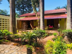 a yellow house with palm trees in a yard at Afro Smile Hotel and Guest House in Jinja
