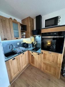 a kitchen with wooden cabinets and a sink and a microwave at Le Nichoir in Le Tholy