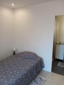 ein Schlafzimmer mit einem Bett mit einer grauen Tagesdecke in der Unterkunft Studio de 14m2 dans une maison in Cagnes-sur-Mer
