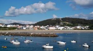 a group of boats in the water near a beach at La casa de Manuel en Ortigueira in A Coruña