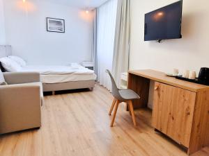 a small room with a bed and a desk with a chair at Hotel Baltic Sun in Kołobrzeg