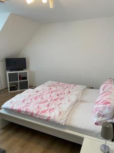 uma cama com um edredão rosa e branco num quarto em Ferienhof Kröger em Bielefeld