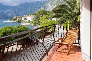 a wooden bench sitting on a balcony overlooking the water at Apartments Djurovic in Kotor