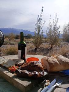 una mesa con una botella de vino y un poco de pan en Cabañas Angualasto en Uspallata