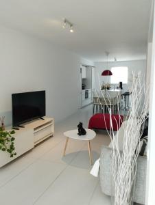 a white living room with a tv and a red couch at The LOFT IBIZA in Ibiza Town
