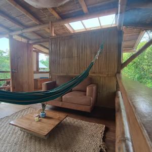 a hammock in a room with a couch and a table at Maracumbo Lodge in Mompiche