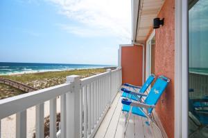 two blue chairs sitting on a balcony overlooking the beach at Life's A Beach Townhouse in Navarre