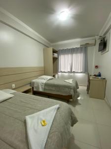 a hotel room with two beds and a window at North Hotel - Aeroporto in Chapecó