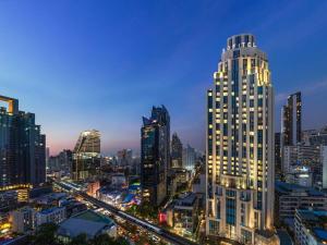 un perfil urbano con un edificio alto por la noche en Sofitel Bangkok Sukhumvit, en Bangkok