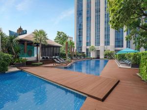 una piscina con terraza de madera y un edificio en Sofitel Bangkok Sukhumvit en Bangkok