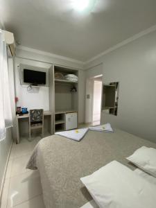 a white bedroom with a bed and a desk at North Hotel - Aeroporto in Chapecó