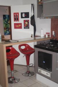 a kitchen with two red stools in front of a counter at AnaLuiza Smarthome in Sao Jose do Rio Preto