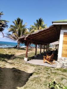 una cabaña en la playa con sillas y el océano en La Princesa de La Isla en Big Corn Island