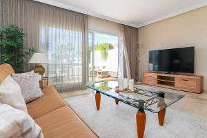 a living room with a couch and a tv at Los Monteros Palm Beach - sea & pool view in Marbella