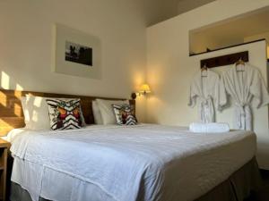 a bedroom with a bed with white clothes hanging on the wall at Pousada do Príncipe in Paraty