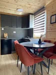a kitchen with a table and some red chairs at Tiny house Neny Fruška gora in Velika Remeta