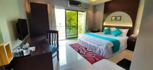 Dormitorio con cama, escritorio y TV en D'more Sreemangal Hotel & Resort en Sreemangal