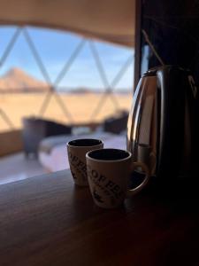 due tazze di caffè sedute su un tavolo accanto a un tostapane di Angelina Luxury Camp ad Aqaba