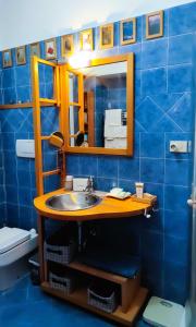 a blue tiled bathroom with a sink and a mirror at Euforbia House in Lido di Ostia