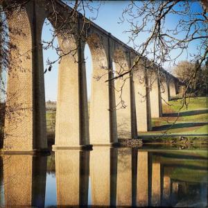 a bridge with pillars in the water next to a body of water at Le Prieuré du Vigeant in Le Vigeant