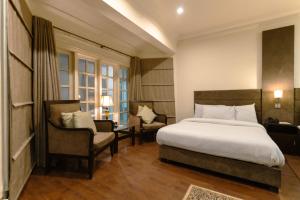 une chambre d'hôtel avec un lit et deux chaises dans l'établissement Shelton Rezidor House Peshawar, à Peshawar