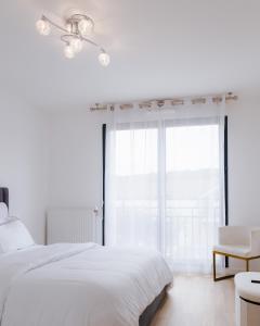 ein weißes Schlafzimmer mit einem Bett und einem Fenster in der Unterkunft Appartement luxueux, neuf et équipé à VERSAILLES, ST CYR L'ÉCOLE in Saint-Cyr-lʼÉcole
