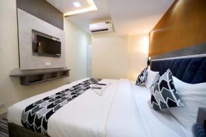 a bedroom with a large bed with a tv on the wall at N.M. Hotel in Mumbai