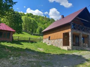 ein Holzgebäude mit einem Zaun neben einem Feld in der Unterkunft Синевирський Краєвид in Synewyr