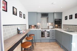 a kitchen with blue cabinets and bar stools at Poppyline Mews in Sheringham