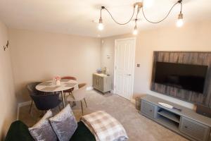 a living room with a tv and a table with chairs at Poppyline Mews in Sheringham
