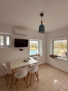 a dining room with a white table and chairs at Eleon Luxury Villa in Karpathos Town