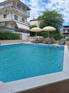 a swimming pool with chairs and umbrellas next to a building at Hotel Victoria in Olympic Beach