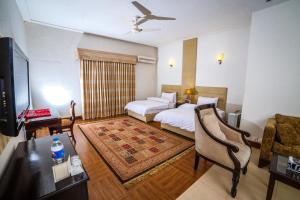 una camera d'albergo con letto, scrivania e TV di Shelton House Peshawar a Peshawar