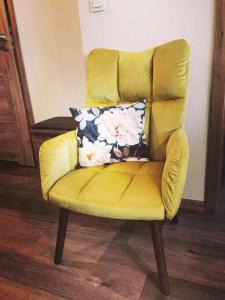 a yellow chair with a pillow on top of it at Apartament Olecko Centrum in Olecko