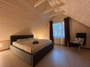 a bedroom with a bed and a chair and a window at River bank vacation home in Jūrmala