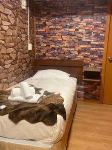 Cama en habitación con pared de piedra en Hostal Queltehue en Ancud