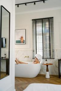 a woman sitting in a bath tub in a bathroom at Damson - Machne Yehuda Hotel in Jerusalem