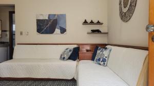 sala de estar con 2 sofás blancos en Piemonte Flat Serra Negra en Serra Negra