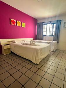 1 dormitorio con 1 cama grande en una pared de color rosa en Pousada Pedras do Porto, en Porto de Galinhas