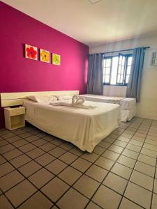 a bedroom with a large bed in a pink wall at Pousada Pedras do Porto in Porto De Galinhas +50 photos