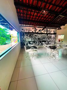 a room with white chairs and a table and a wall at Pousada Pedras do Porto in Porto De Galinhas