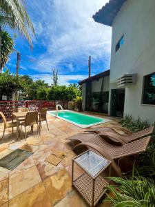 a patio with a table and chairs and a swimming pool at Pousada Pedras do Porto in Porto De Galinhas