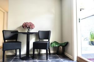 Apartment on idyllic Bygdøy with free parking في أوسلو: طاولة طعام مع كرسيين و مزهرية من الزهور
