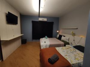a small room with two beds and a television at Pousada Casa dos Gattos - Próx ao Aeroporto Guarulhos in Guarulhos +16 photos