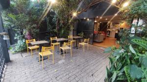 a patio with tables and chairs in a garden at Pousada Casa dos Gattos - Próx ao Aeroporto Guarulhos in Guarulhos