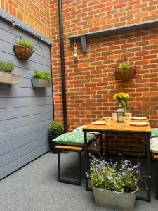 a patio with a table and chairs and a brick wall at Poppyline Mews in Sheringham