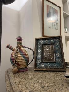 un cadre photo et un vase sur un comptoir à côté d'une photo dans l'établissement Marasi Catania, au Caire