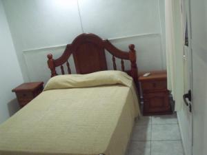 Habitación pequeña con cama y mesita de noche en Hotel Cabañas Tio Lucas en Ituzaingó