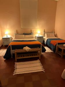 2 camas en una habitación con 2 mesas y 2 lámparas en Casa Los Nogales en Cafayate